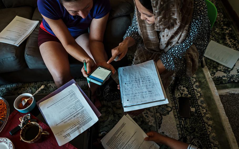 Sadye Katherine Scott-Hainchek, 36, left, a volunteer, helps Afghan refugees such as Medina Mohammadi, 28, fill out asylum paperwork in Des Moines, Iowa, on Aug. 7, 2022.