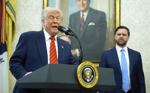 President Trump speaks at a podium while Vice President Vance looks on.