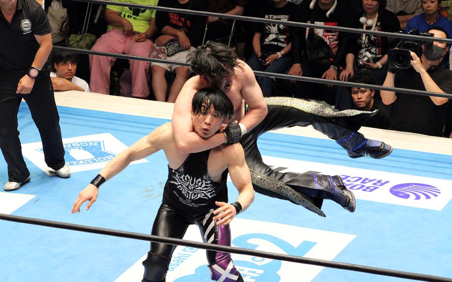 Professional wrestlers grapple within a wrestling ring.
