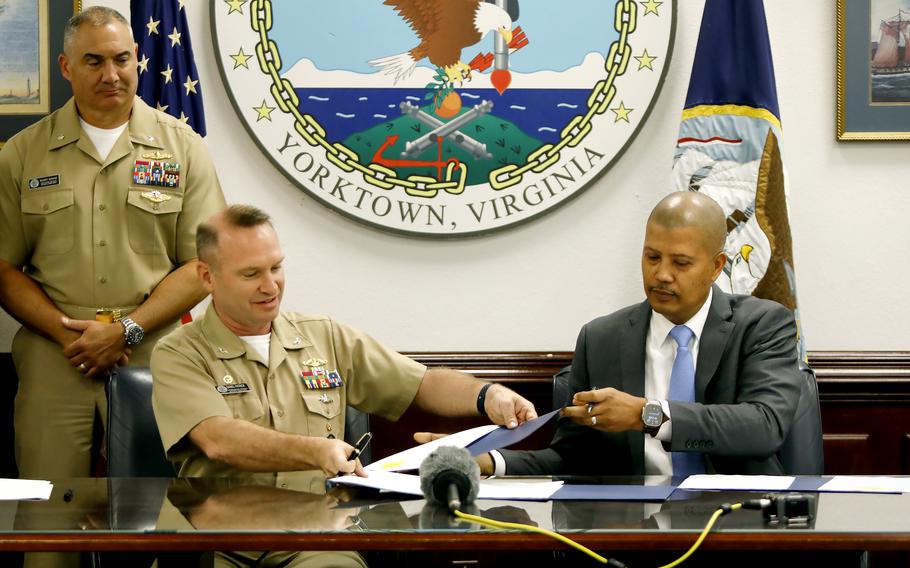 Three people at a desk, two of them seated.