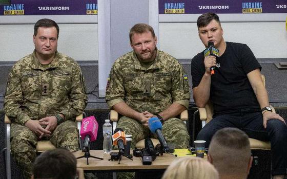 Maksim Kuzminov, right, with representatives of the Defence Intelligence of Ukraine, Andrii Yusov, at left, and Artem Shevchenko, left and right respectively, during a news conference at the Ukraine Media Center.