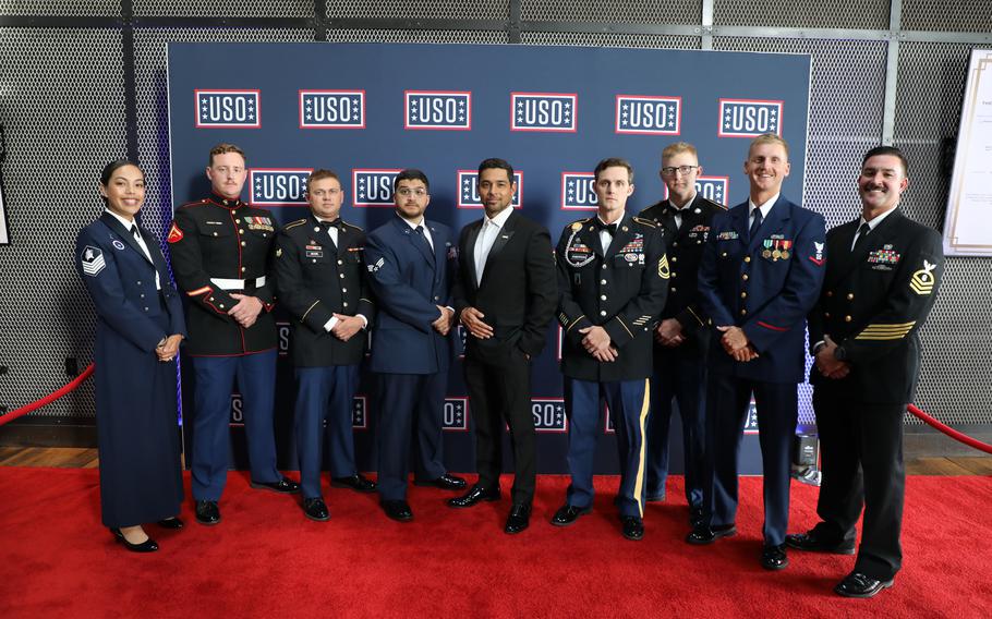 Eight service members pose on the USO’s red carpet with actor Wilmer Valderrama