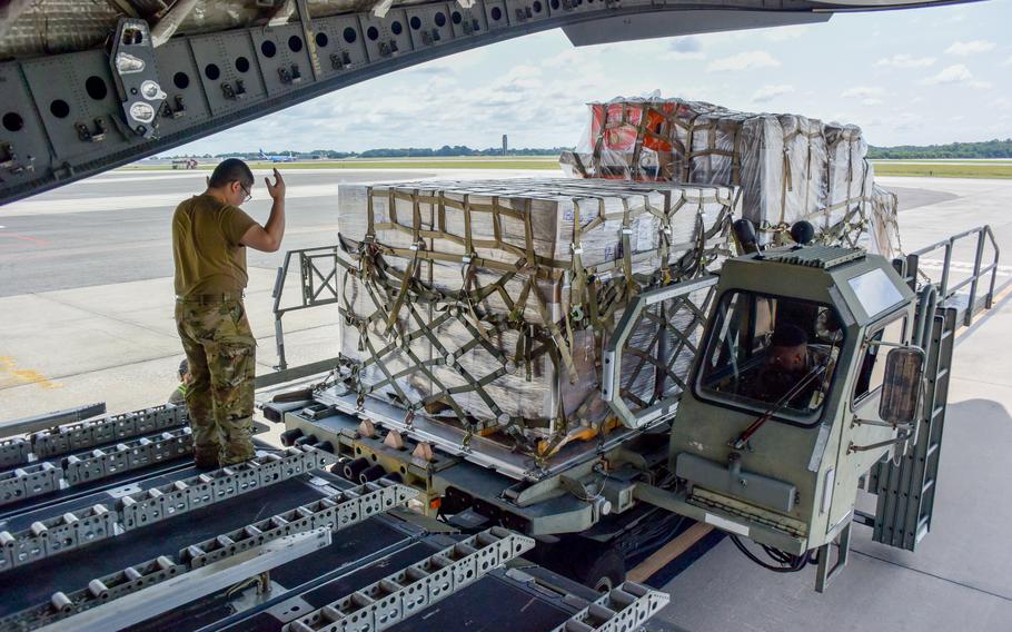 An airman directs a cargo  onto an aircraft
