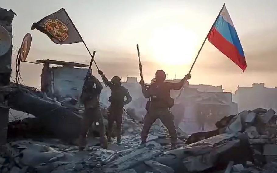 In this screen grab taken from video released by Prigozhin Press Service on Saturday, May 20, 2023, Yevgeny Prigozhin’s Wagner Group military company members wave a Russian national and Wagner flag atop a damaged building in Bakhmut, Ukraine.