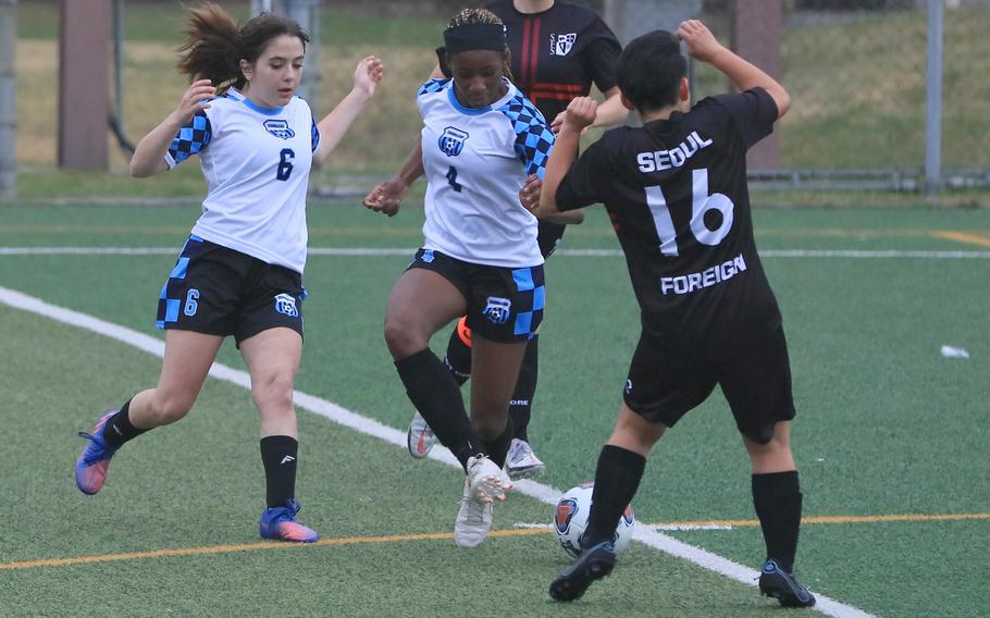 Osan's Tatiana Lunn boots the ball away from Seoul Foreign's Cara Kim as Cougars teammate Elyanna Koch moves in to help during Wednesday's Korea girls soccer match. The Crusaders won 5-1.