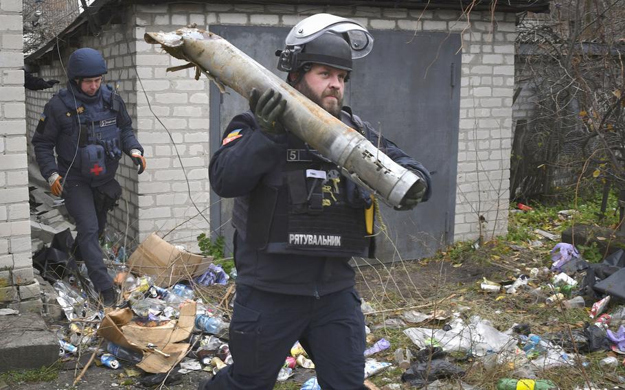 A Ukrainian combat engineer carries a part of a projectile during a demining operation in a residential area in Lyman, Donetsk region, Ukraine, Wednesday, Nov. 16, 2022. 