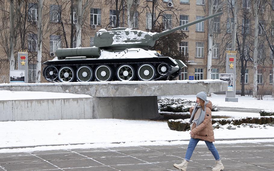 A young woman walks past a World War II-era Soviet T-34 tank at an outdoor commemorative display extolling the battles and victories of the Soviet Red Army in liberating the Soviet Union against Nazi Germany occupation during World War II on Jan. 25, 2022, in Kyiv, Ukraine.