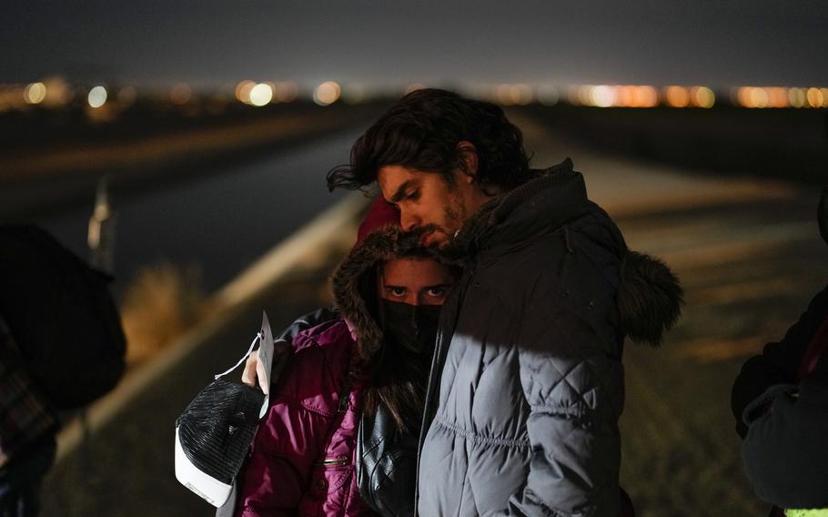 Cuban migrant Mario Perez holds his wife as they wait to be processed to seek asylum after crossing the border into the United States on Jan. 6, 2023, near Yuma, Ariz. U.S. authorities have seen a 97% decline in illegal border crossings by migrants from Cuba, Haiti, Nicaragua and Venezuela since Mexico began accepting those expelled under a pandemic-era order, the Biden administration said Wednesday, Jan. 25, 2023.