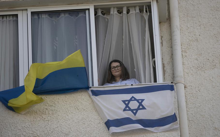 Tatyana Prima, who fled Mariupol, Ukraine, poses for a portrait with her national flag and the Israeli flag she displays outside of her apartment window in Ashkelon, southern Israel, Wednesday, Nov. 8, 2023.
