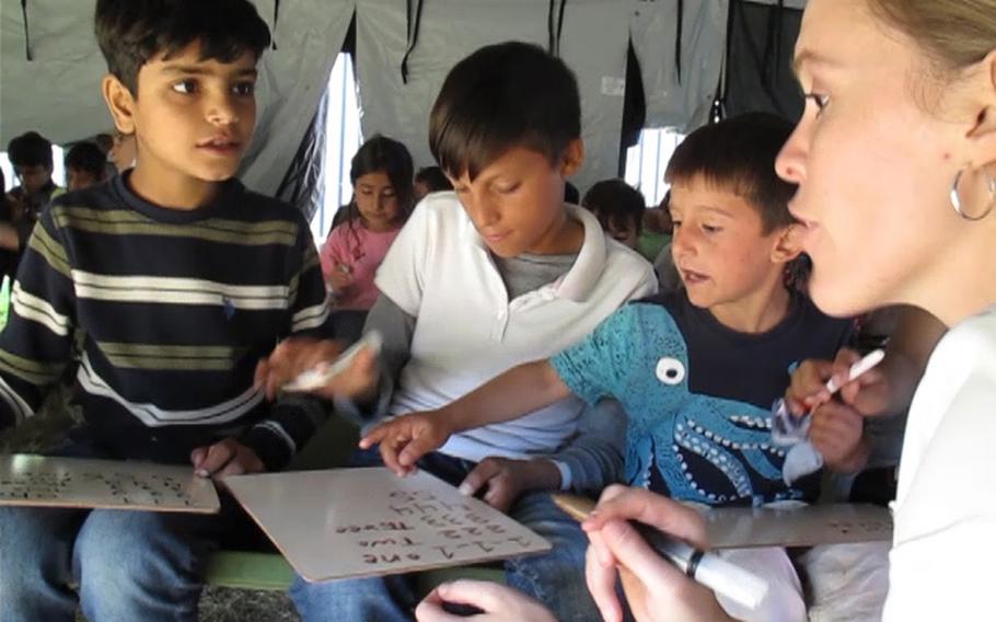 English teacher Morgan Guinn, right, works with three Afghan boys during a writing class at Rhine Ordnance Barracks in Kaiserslautern, Germany, Sept. 27, 2021. Volunteers and soldiers have been introducing the 5,400 Afghans who are temporarily housed at ROB to aspects of American life. 