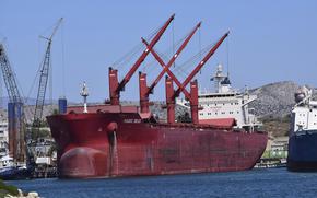 A red boat is moored in a bay.