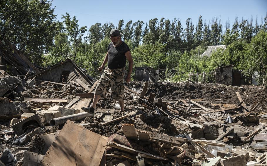 Yuriy Makagon stands amid the rubble of his neighbor's home in the eastern Ukrainian village of Kostiantynivka on June 10, 2022.