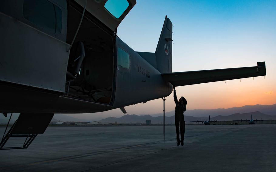 Afghan air force Capt. Safia Ferozi jumps to reach the rear elevator of her aircraft during a preflight check in Kabul, Afghanistan, in 2017. Ferozi was a C-208 pilot in the Afghan air force and regularly trained with U.S. instructor pilots.