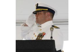 A man in a Coast Guard uniform seen from the shoulders up, saluting.