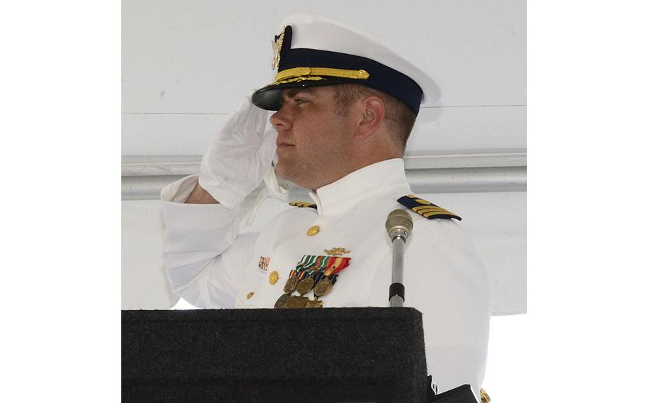 A man in a Coast Guard uniform seen from the shoulders up, saluting.