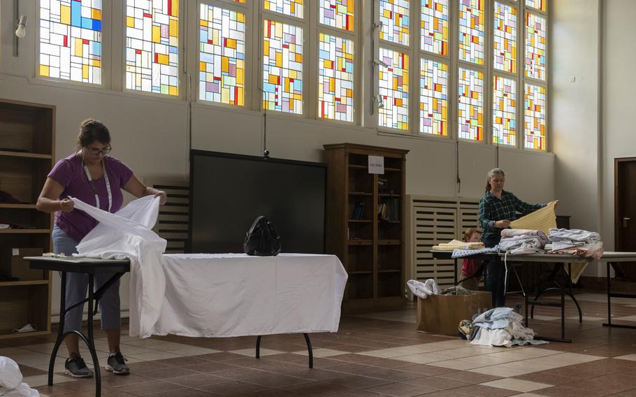 Ann Llams, left, and Maggie Mayfield prepare cloth that volunteers will turn into prayer garments for Afghan refugees at Ramstein Air Base on Aug. 26, 2021. 