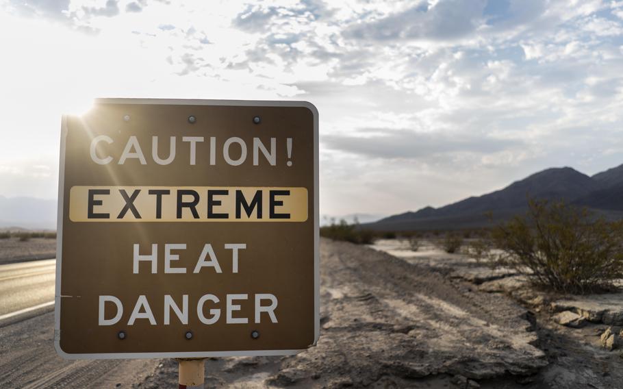 With the Amargosa Mountain Range in the background at sunrise, a sign warns park visitors of "extreme heat danger" along Highway 190 during a weekend of extreme record breaking high temperatures reaching 135 degrees Fahrenheit in Death Valley National Park, Calif., on July 11, 2021. 