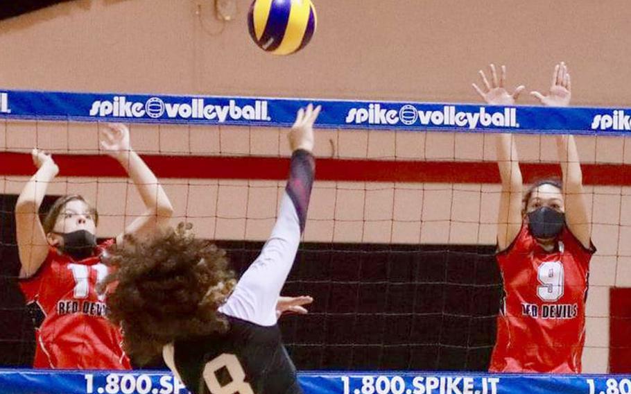 Zama's Erika Farley spikes through the double block of Nile C. Kinnick's Kathryn Withers and Millie Howell during Saturday's match. The Trojans won in five sets.