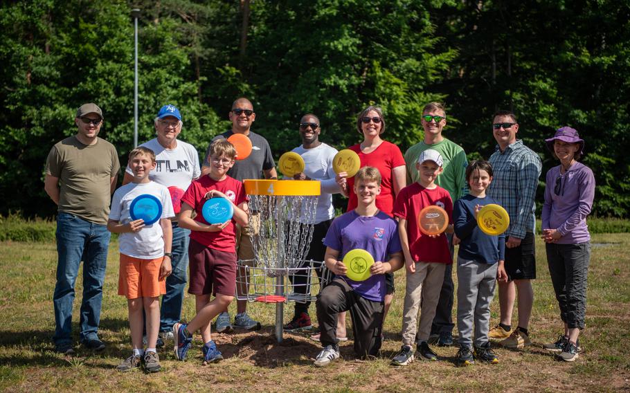 Volunteers pose with flying discs on a disc golf course.