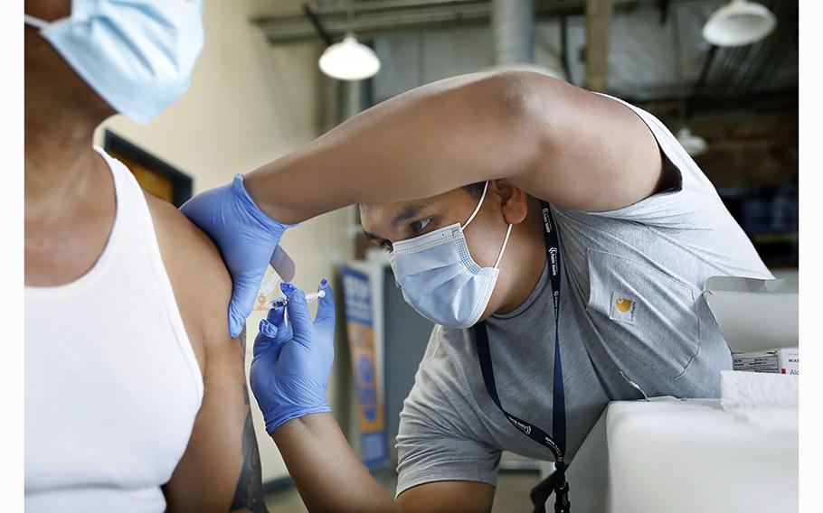 Jeremy Oyague, right, a registered nurse with The Los Angeles Department of Public Health, administers a COVID booster at a vaccination clinic to immunize people against monkeypox and COVID at The Village Mental Health Services in Los Angeles, a site run by The People Concern. 