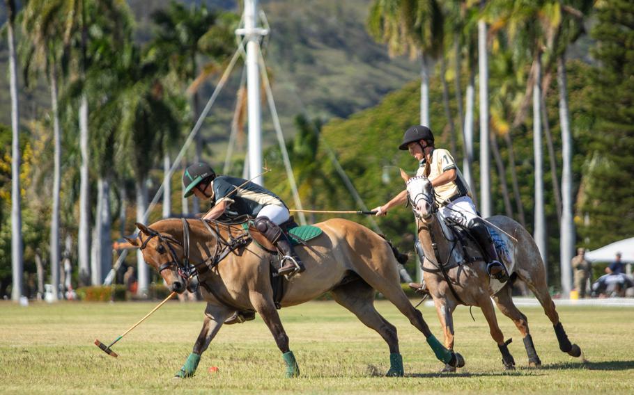 Two polo players on horses, with both animals running and the riders leaning down.