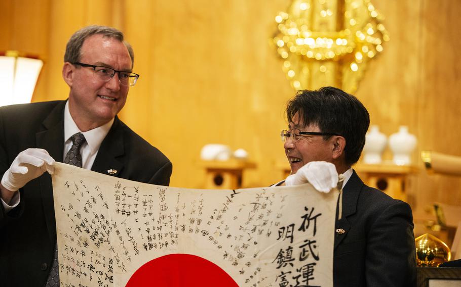 Chris Johnson and Toshinari Myochin hold Norito Myochin's "good luck flag" during a ceremony at Gokoku Shrine in Hiroshima, Japan, Sunday, Dec. 4, 2022.