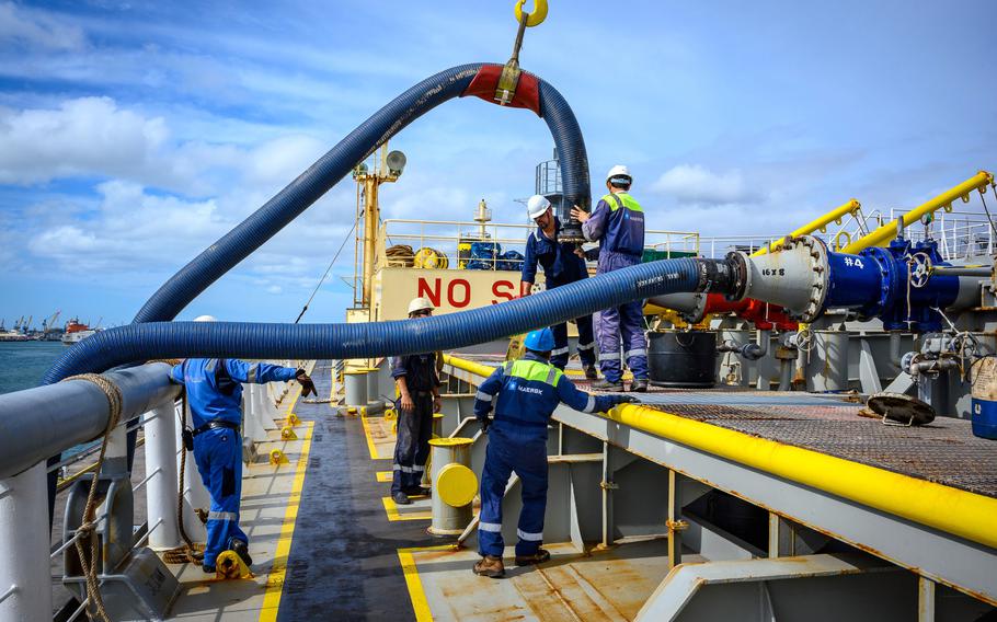 Workers connect fuel lines to a merchant tanker while transferring fuel from the Red Hill Bulk Fuel Storage Facility on Nov. 16, 2023.