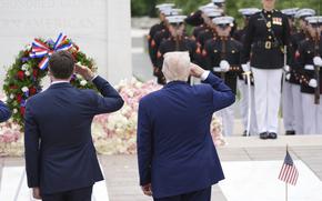 Trump and another man, backs to the camera, salute.