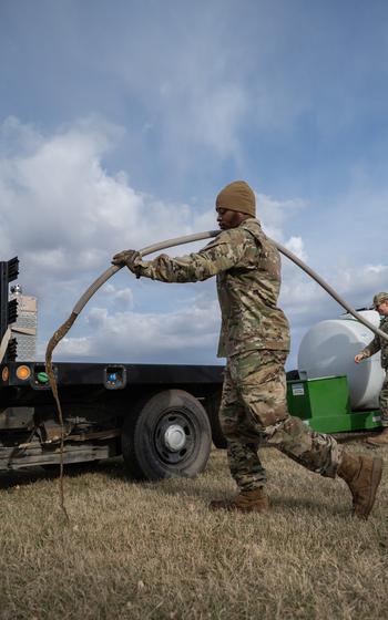 An airman works to fill a hole created by ground squirrels.