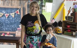 A mom and her son pose for a photo in front of school-themed props in a photo booth.