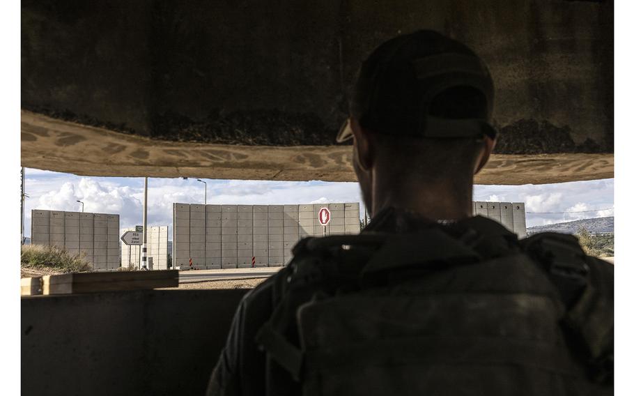 Naveh, an Israeli soldier who was previously fighting in Gaza, guards a road near a cement barrier wall close to the Israel-Lebanon border that was erected after Oct. 7., 2023.