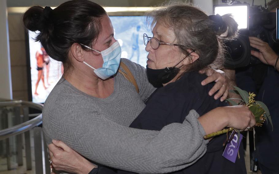 A woman, right, is embraced by. a loved one after arriving on a flight from Los Angeles at Sydney Airport as Australia open its borders for the first time in 19 months in Sydney, Monday, Nov. 1, 2021. International travel will be initially restricted to Sydney's airport because New South Wales has the highest vaccination rate of any state. 