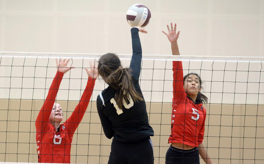 Zama’s Nina Sakamoto-Flack spikes between E.J. King’s Madylyn O’Neill and Ysa Pyryt during Friday’s Japan volleyball match. The Trojans rallied from two sets down to win in five sets.