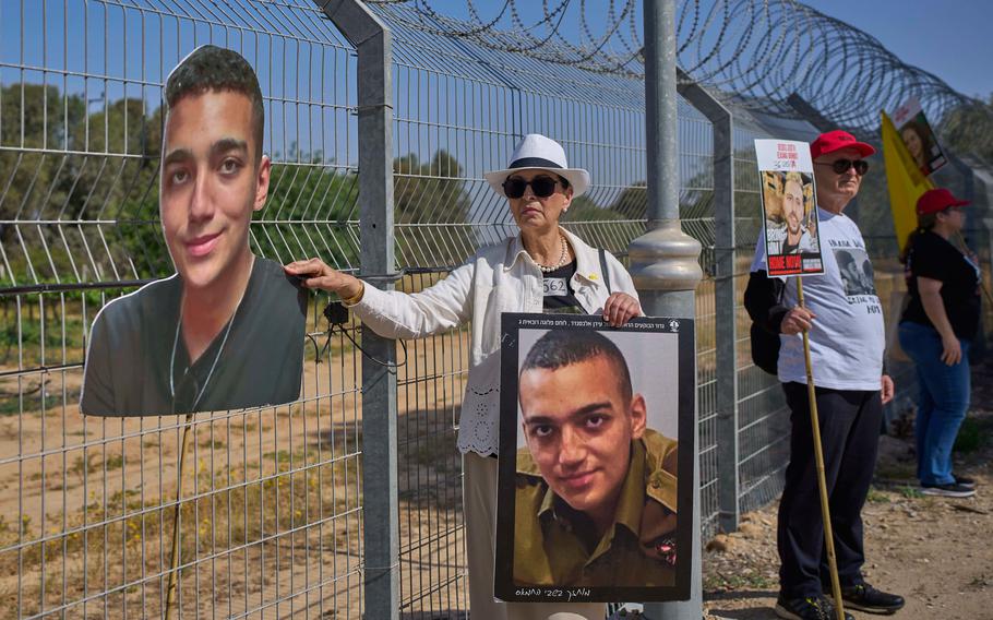 Barch stands at a fence and holds two photos of Edan Alexander.