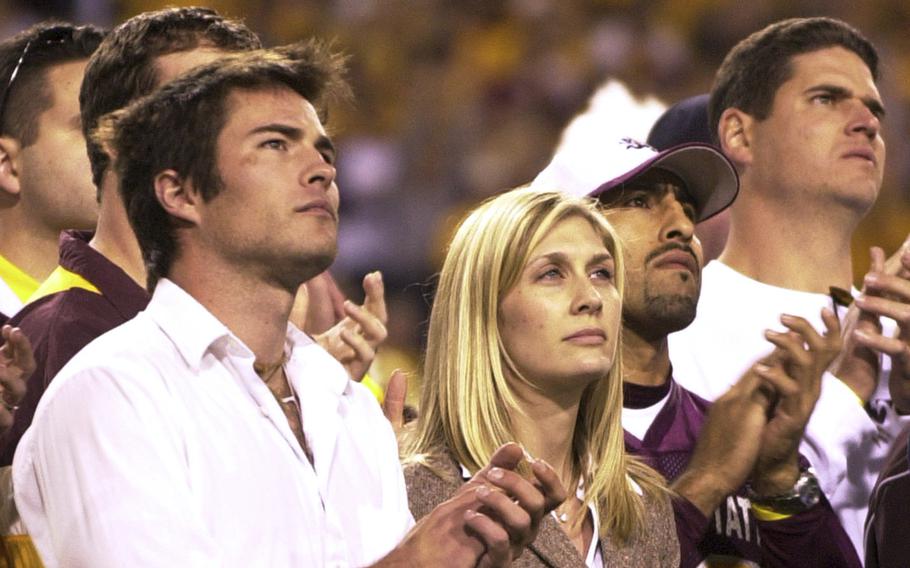 A man and woman applaud as they look ahead.