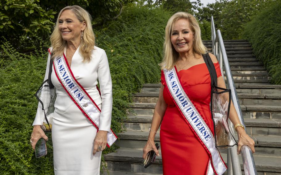 Two women wearing sashes walking down steps.