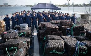 The crew of USCGC Thetis (WMEC 910) poses for a group photo behind more than 28,500 pounds of seized drugs worth more than $211 million at Port Everglades in Fort Lauderdale, Florida, May 29, 2025. The crew seized the illicit drugs in four separate interdictions during a patrol in the Eastern Pacific Ocean. (U.S. Coast Guard photo by Petty Officer 1st Class Diana Sherbs)