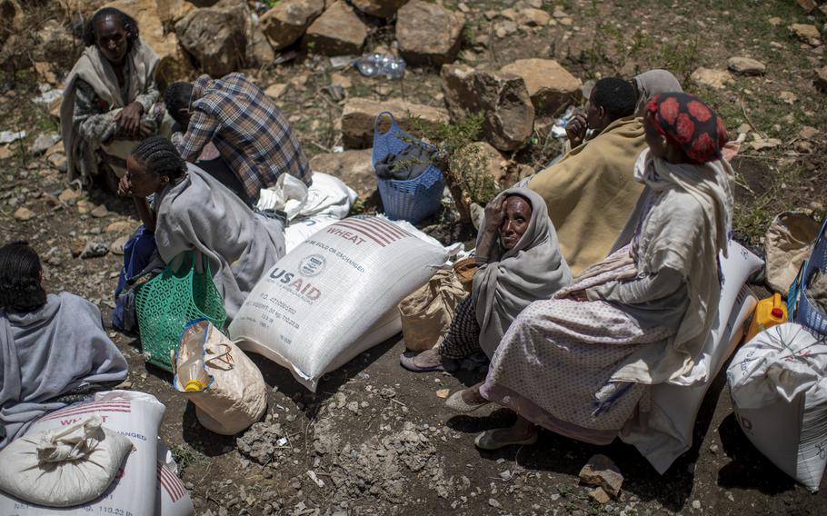 An elderly Ethiopian woman sits next to a sack of wheat after it was distributed to her by the Relief Society of Tigray in the town of Agula, in the Tigray region of northern Ethiopia, on May 8, 2021.