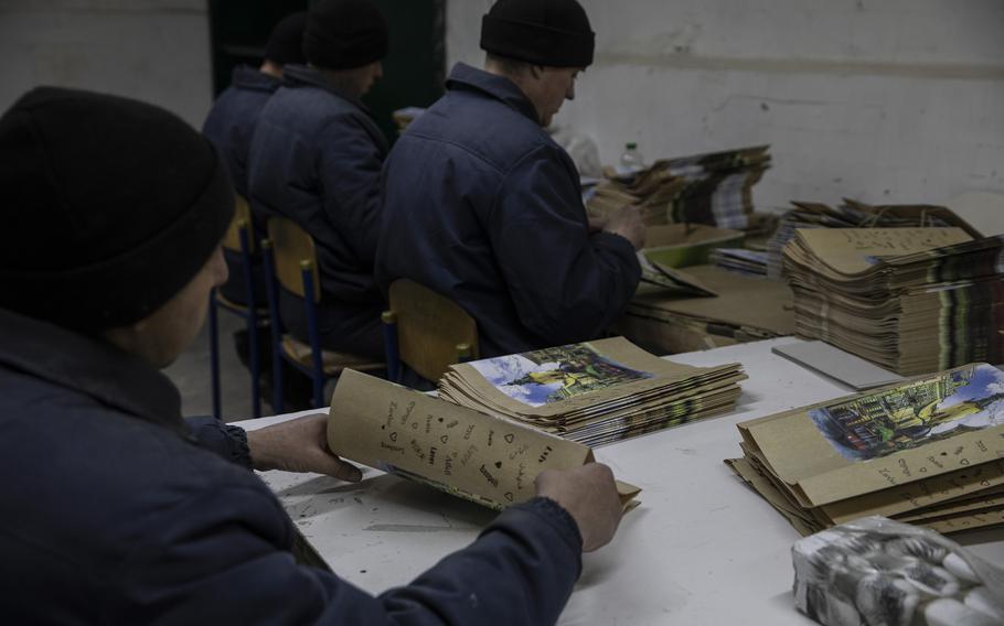 Russian prisoners assemble small, colorful, paper shopping bags.