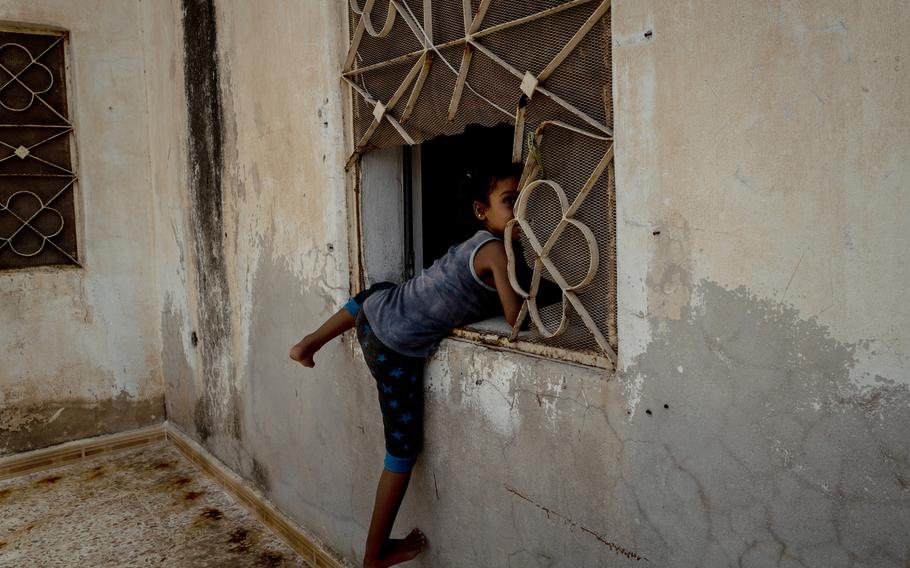 Shaimaa, 5, plays in a window frame at the home of her grandmother, Umm Shaimaa, in Raqqa. Shaimaa, her siblings and her mother, who is Syrian, were all brought back from al-Hol camp to Raqqa as part of a returnee program facilitated by tribal leaders. But children like Shaimaa, who was born to a Saudi father in the Islamic State, have no documentation and no official nationality, as citizenship can only be transferred through the father. 