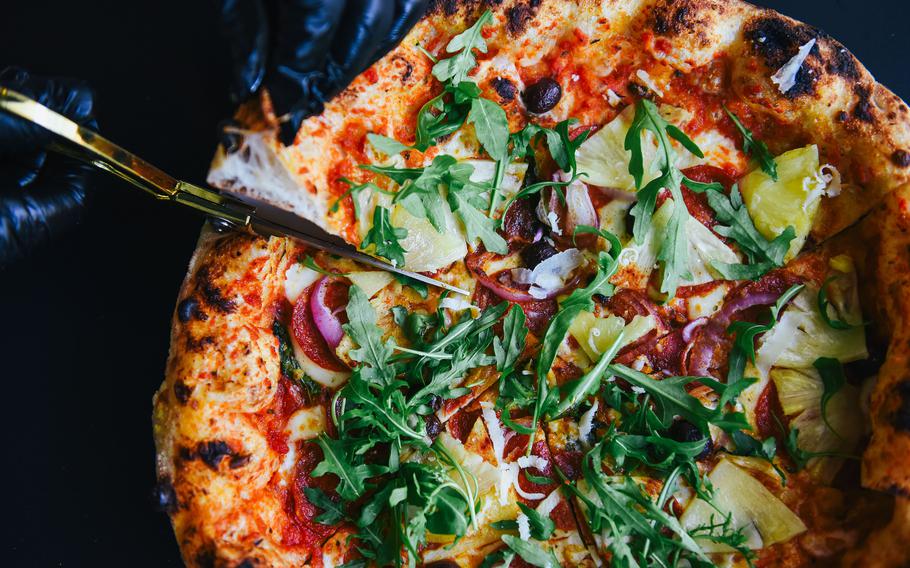 A pizza is cut into portions with scissors.