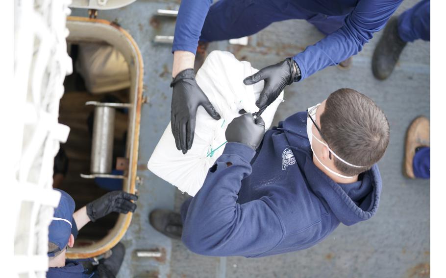 U.S. Coast Guard Petty Officer 3rd Class Robert Coy, a damage controlman assigned to Coast Guard Cutter Thetis, passes bales of illicit drugs interdicted by the unit’s law enforcement team, Jan. 30, 2024, in the Central Caribbean Sea. 