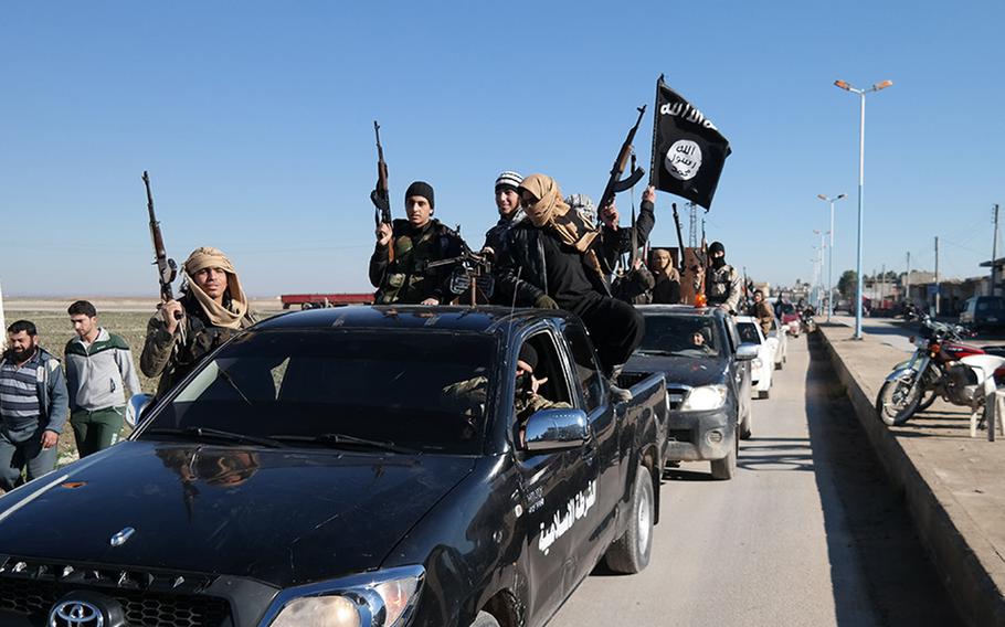 Men holding guns stand in the back of a pickup truck.