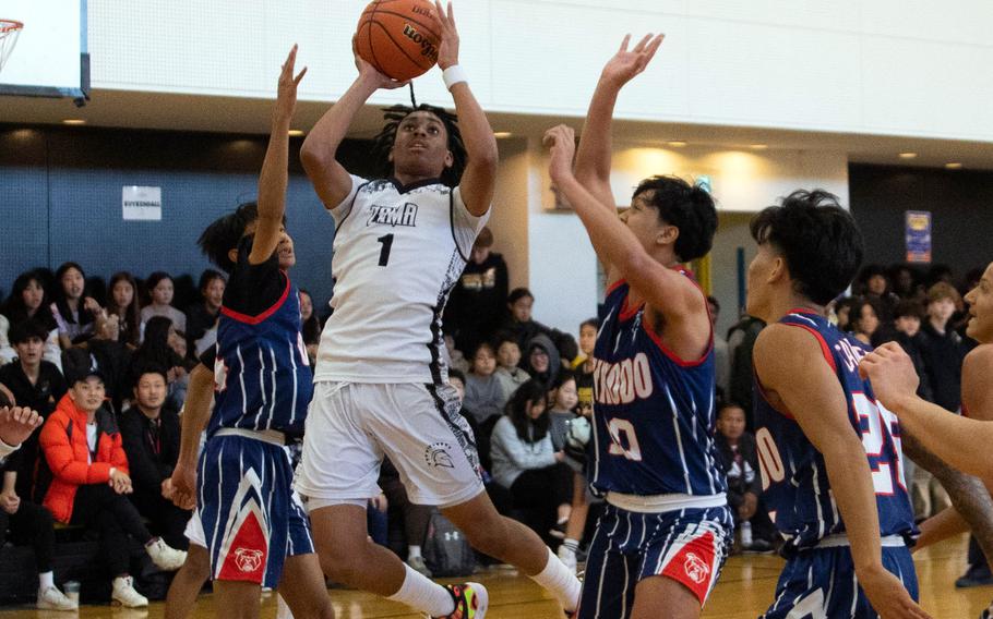 Zama's Ayden Helton pulls up for a shot between Okkodo defenders. The Trojans rallied for a 32-29 win.