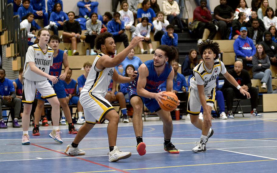Ramstein's Israel Rouse picks up the ball to shoot while Stuttgart's Trenton Jackson, center, and Ismael Anglada-Paz defend during Saturday's game at Ramstein High School on Ramstein Air Base, Germany. 