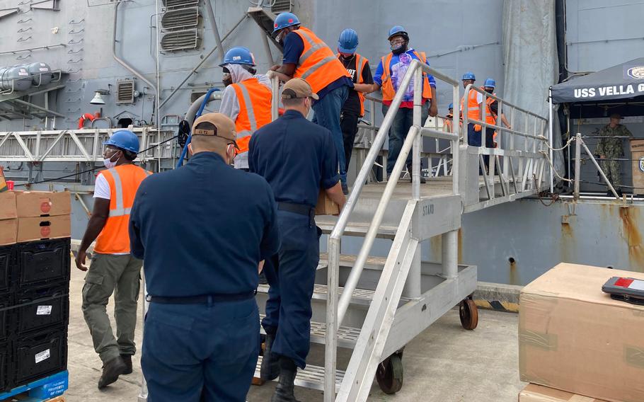 USS Vella Gulf sailors carry on a load of produce as the cruiser prepares to head out to sea again.