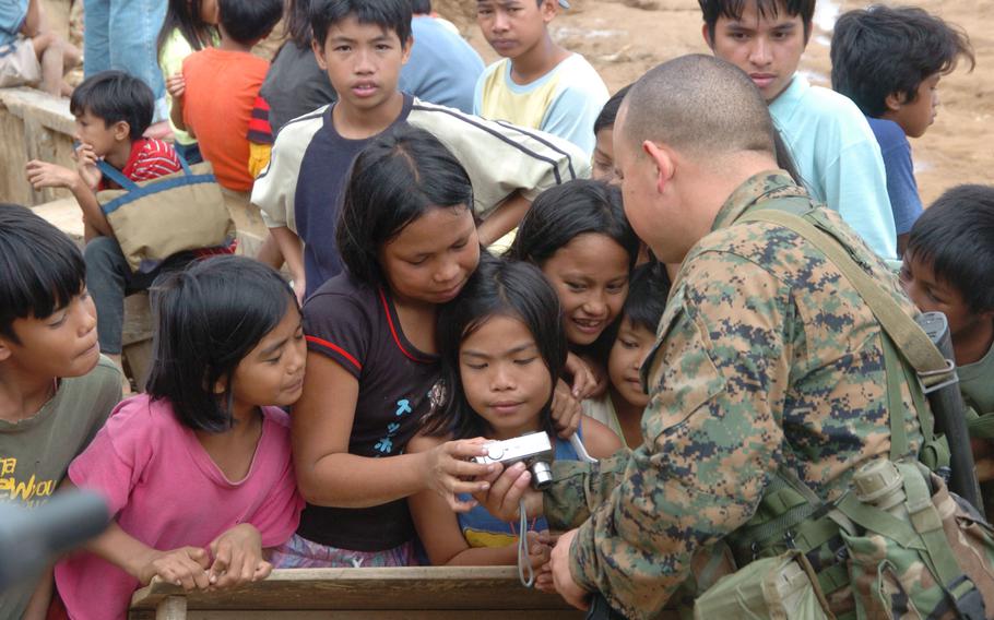 A Marine working at a distribution site for relief aid shows local girls their photo taken on his digital camera. The Marines, sent to
the Philippines to provide and transport humanitarian aid, spent time interacting with residents when possible.