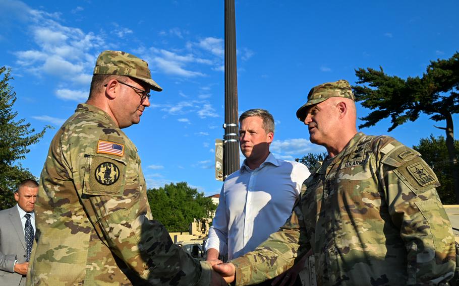 Mingus shakes the hand of a soldier with Driscoll standing by.