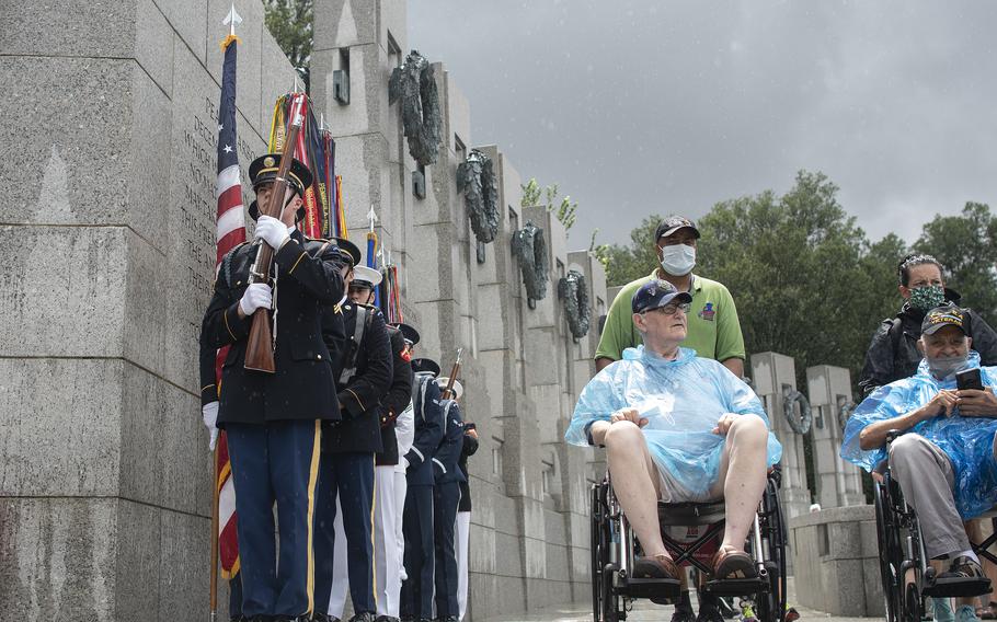 Members of a military honor guard stand at attention as Army veteran Ron Raczak arrives at the World War II Memorial in Washington, D.C., on Wednesday, Aug. 18, 2021, just as a downpour of rain subsides prior to an Honor Flight ceremony that paid tribute to veterans from World War II, the Korean War and the Vietnam War.
