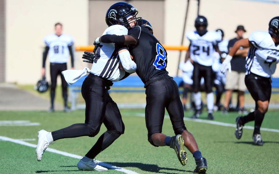 Zama's Will Schmiedel, getting hit by Osan's Malik Davis, ran for two touchdowns and passed for two more during the Trojans' 49-16 win over the Cougars.